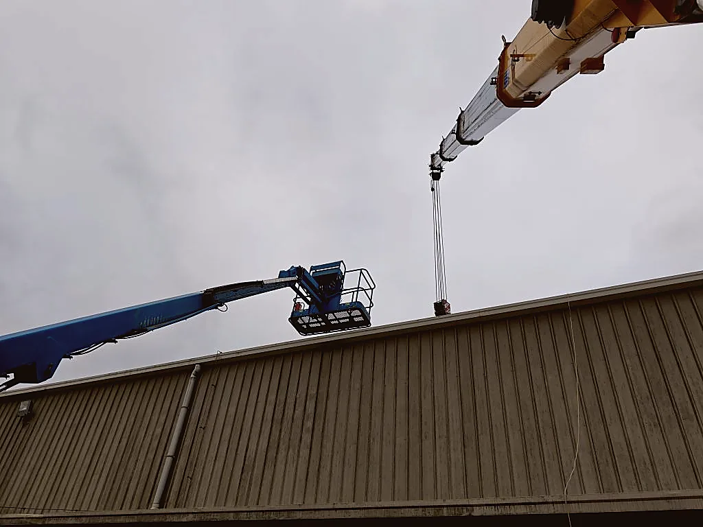 Two boom cranes working together on a construction site