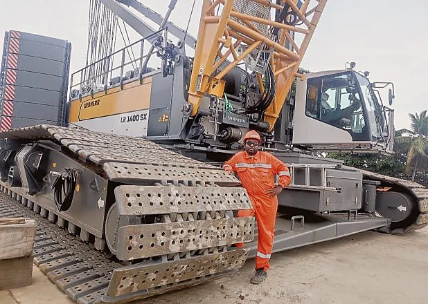 Muthuraj Jeyabal in orange PPE beside Liebherr LR 1400 SX crawler crane